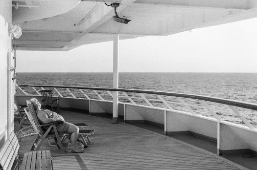 A passenger soaks up the last bit of sun of the day at the aft of the ship